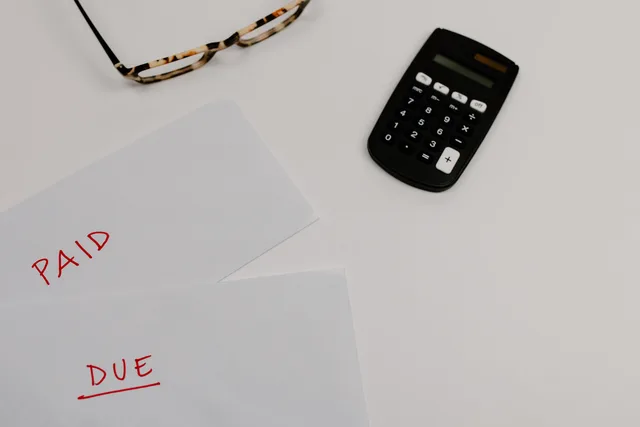 Top view of financial papers labeled 'Paid' and 'Due' beside a calculator and glasses. Five shifts reshaping the subscription commerce market outlook