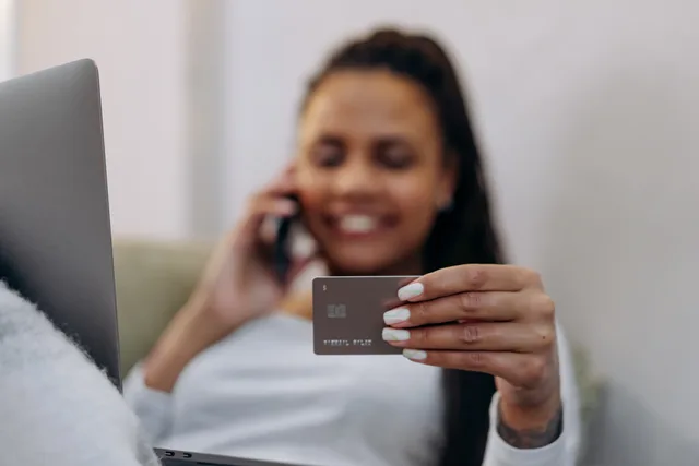 Smiling woman with credit card and smartphone, shopping online at home. Choosing subscription commerce pricing models without guessing at margins