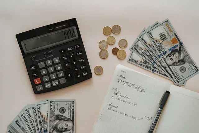 Flat lay of calculator, cash, coins, and handwritten notes for budget planning. Modelling subscription commerce return on investment in pounds